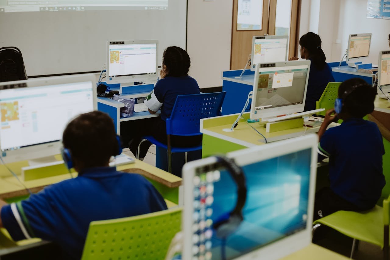 Children engaged in learning at computers in a modern classroom setting, promoting digital literacy.